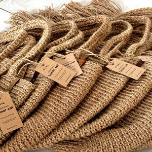 Puede incluir: Una pila de varias bolsas de crochet de yute marr&oacute;n con asas. Cada bolsa tiene una etiqueta que dice "Lunar Cat". Las bolsas est&aacute;n hechas de un material grueso y tejido y tienen un detalle de flecos en la parte superior.