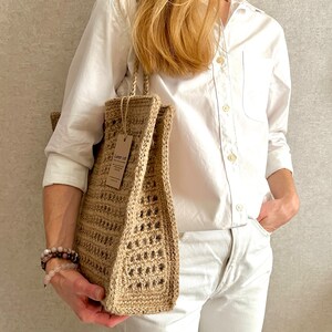May include: A brown and tan crocheted tote bag with a brown leather tag that says "Linen Co."