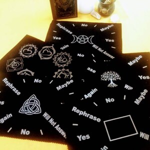 May include: Four black felt pendulum boards with white text and symbols. The boards include the words "Rephrase", "Yes", "No", "Maybe", "Try Again", "Will Not Answer", and "Again".