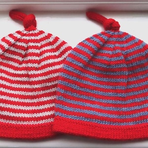 May include: Two striped knitted hats with red and white stripes and red and blue stripes. The hats have a knot at the top.