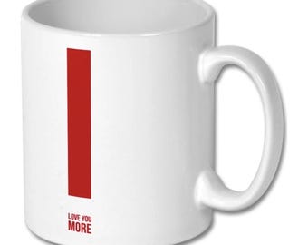 May include: A white ceramic mug featuring a large, vertical red letter I on the front. Below the letter, the text LOVE YOU MORE is printed in a smaller, bold red sans-serif font. The mug has a standard cylindrical shape and a side handle.