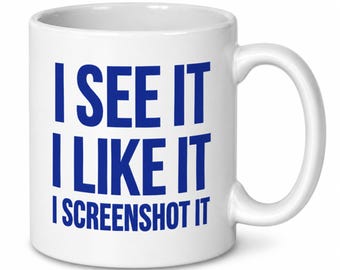 May include: A white ceramic mug with a handle on the right side. The front of the mug features bold blue text that reads: I SEE IT, I LIKE IT, I SCREENSHOT IT. The design is printed in a clean, sans-serif font centered on the smooth surface.