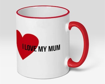 May include: A white ceramic mug featuring a red heart graphic and the black text I LOVE MY MUM. The mug has a bright red handle and a matching red rim around the top edge, providing a bold contrast against the white surface of the vessel.