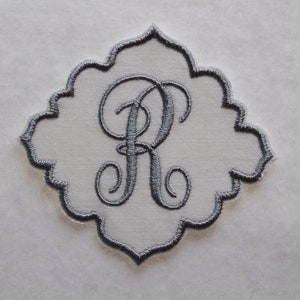 May include: A gray embroidered monogram letter "R" on a white fabric patch. The patch has a scalloped edge and is suitable for sewing onto clothing or other fabric items. The embroidery is detailed and elegant.