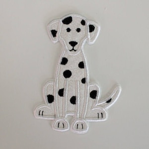 May include: White embroidered patch of a sitting Dalmatian dog with black spots. The dog has a black nose, eyes, and ears. The patch is outlined with white stitching and has a tail.