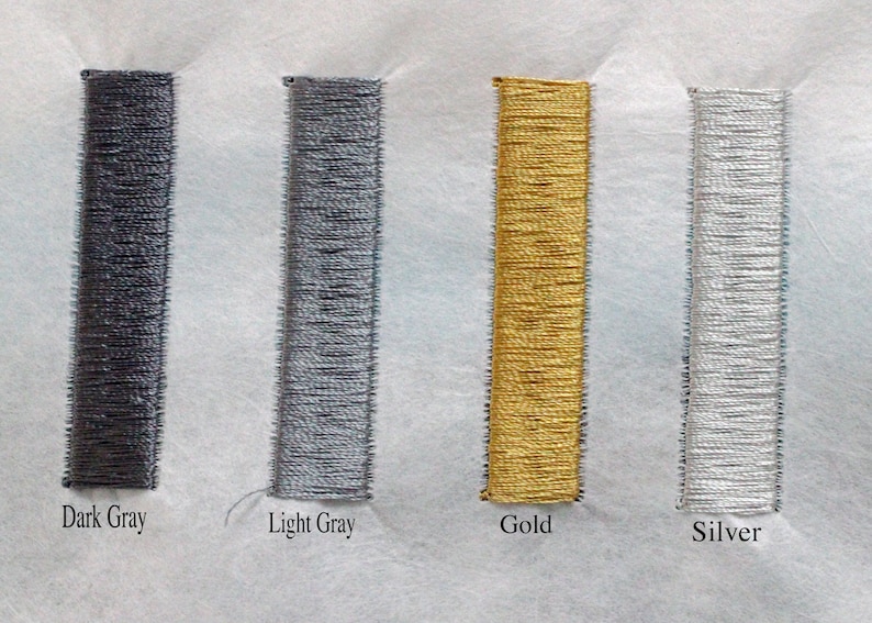 May include: Close-up of four embroidered rectangles in dark gray, light gray, gold, and silver. The rectangles are vertically aligned and labeled with their respective colors. The embroidery is on a white fabric.