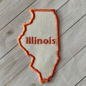 May include: An orange embroidered patch in the shape of the state of Illinois with the word "Illinois" stitched in orange on the patch.
