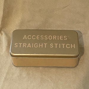 May include: A gold metal tin with the words "Accessories Straight Stitch" printed on the top.
