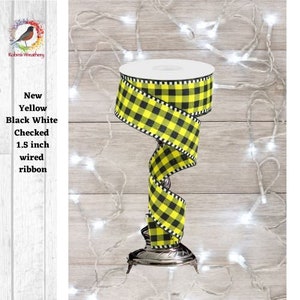 Op de afbeelding: Nieuw geel en zwart geblokt lint met draad, 1,5 inch breed. Het lint is gemaakt van geel en zwart buffalo plaid met een witte rand. Het is om een zilveren standaard gewikkeld.