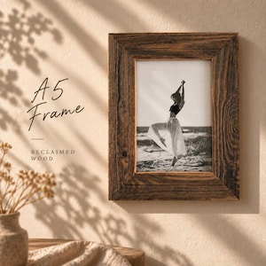 May include: A rectangular A5 picture frame made of dark brown reclaimed wood with a visible grain texture. The frame contains a black and white photograph of a person dancing on a beach. The text A5 Frame and Reclaimed Wood is visible.