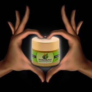 Könnte beinhalten: Ein goldener Behälter mit einem grünen Blattlogo und dem Text "Scents 4 My Soul" sowie der Website "www.scents4mysoul.com". Der Behälter ist von zwei Händen umgeben, die eine Herzform bilden.