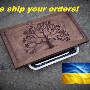 May include: A wooden serving tray with a carved tree design. The tray is dark brown and has a rectangular shape. The text "We ship your orders!" is in yellow. The Ukrainian flag is in the bottom right corner.
