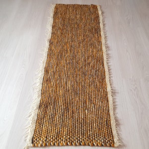May include: A long, narrow, brown and white woven rug with a fringed edge.