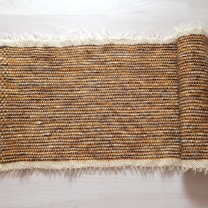 May include: A rolled-up brown and white woven rug with a fringed edge.