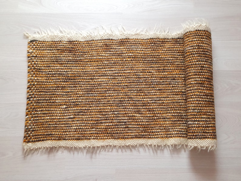 May include: A rolled-up brown and white woven rug with a fringed edge.