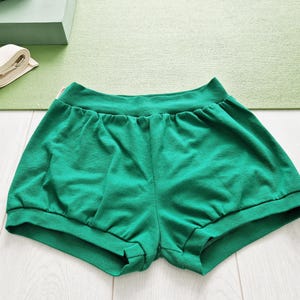 May include: Green cotton shorts with a gathered waist and a wide leg.