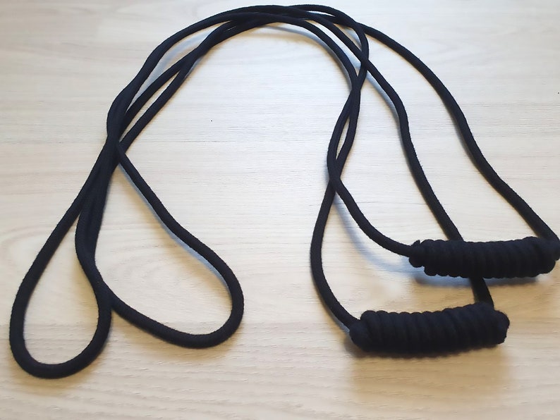 May include: Black resistance bands with padded handles. The bands are made of a thick, durable material and are designed for strength training and exercise. The handles are wrapped for a comfortable grip.