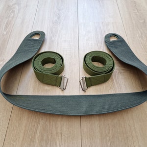 May include: Two green canvas straps with metal buckles and loops. The straps are rolled up and tied together.