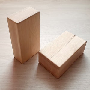 May include: Two wooden blocks, one stacked on top of the other. The blocks are light brown and have a smooth, natural finish.