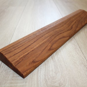 Op de afbeelding: Een lange, bruine houten helling met een lichte helling. De helling is gemaakt van natuurlijk hout met een gladde afwerking.