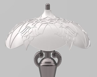 Op de afbeelding: Een zilveren tafellamp met een witte, sierlijke lampenkap. De lamp heeft een hoge, slanke voet met een decoratief ontwerp.