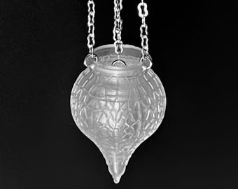 May include: A clear glass hanging lamp with a decorative, intricate pattern. The lamp is suspended from a ceiling by three silver chains.