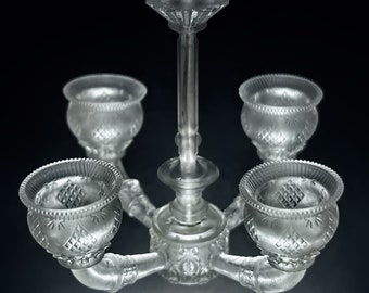 Könnte beinhalten: Ein durchsichtiger Glas-Kronleuchter mit fünf Kerzenhaltern. Der Kronleuchter hat ein dekoratives Design mit einem floralen Muster.