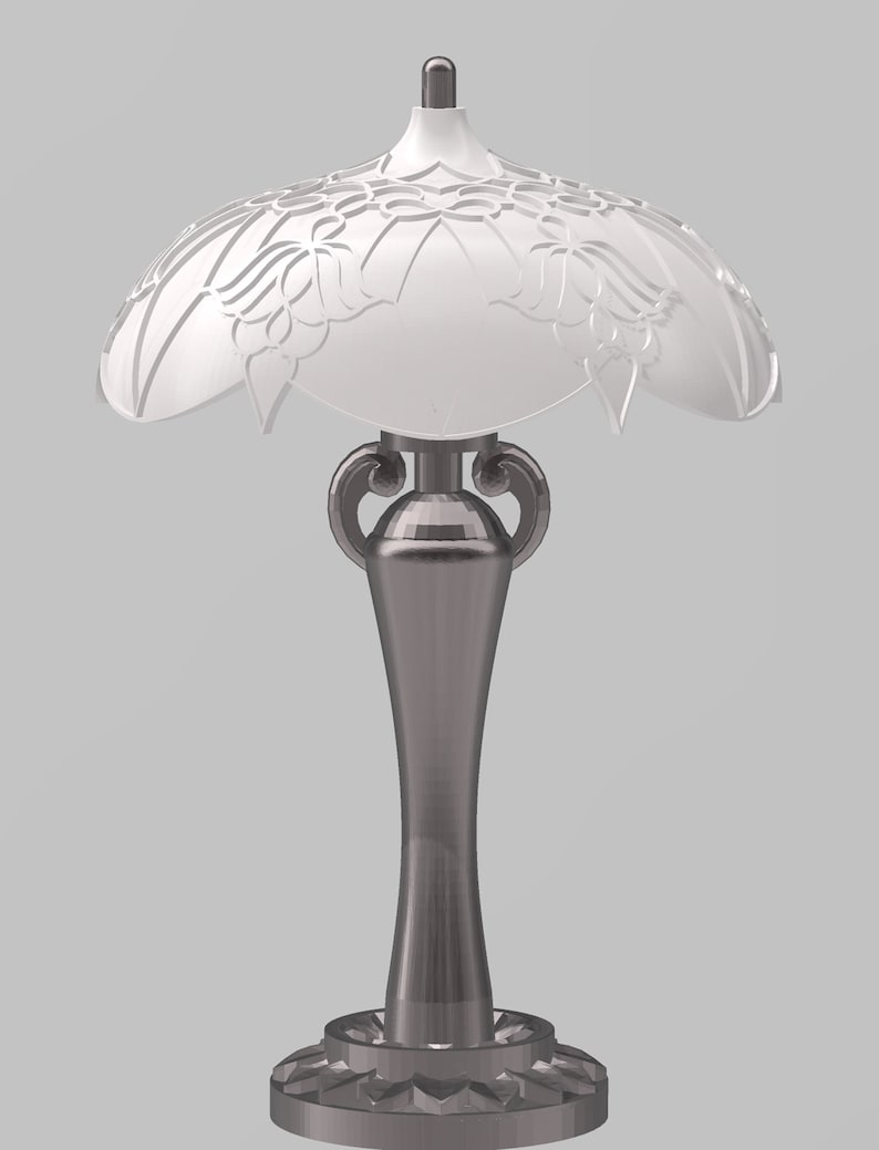K&ouml;nnte beinhalten: Eine silberne Tischlampe mit einem wei&szlig;en, verzierten Lampenschirm. Die Lampe hat einen hohen, schlanken Sockel mit einem dekorativen Design.