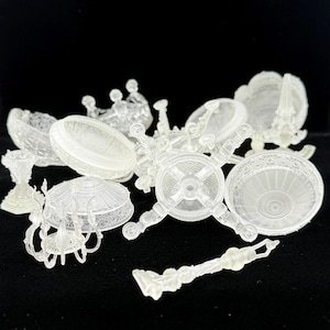 May include: A collection of translucent, 3D-printed miniature objects including ornate bowls, a small chandelier, a crown, and decorative stands. Each piece features intricate, raised patterns and textures, all rendered in a clear, semi-opaque resin material.