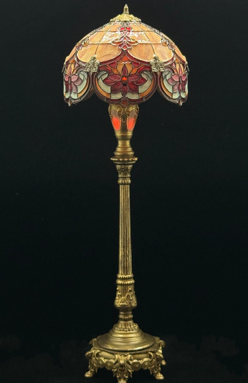 May include: A decorative floor lamp with a stained glass shade. The shade features a floral design in shades of orange, red, and pink. The lamp has a brass-colored base and stem, and stands approximately 60 inches tall.