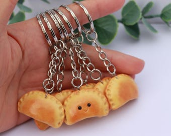 Puede incluir: Un conjunto de cinco llaveros con un pastel sonriente, cada uno unido a una cadena plateada y un llavero plateado.