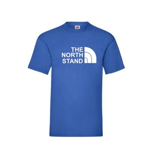 May include: A royal blue t-shirt with a white graphic of the text "THE NORTH STAND" and a mountain range logo.