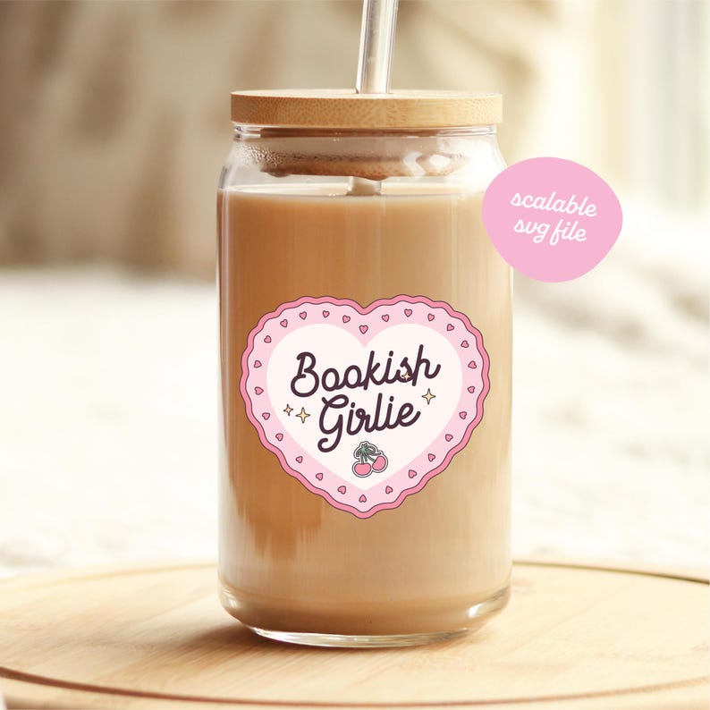 May include: A clear glass tumbler with a bamboo lid and a straw, filled with a light brown beverage. The tumbler features a pink heart-shaped sticker with the words "Bookish Girlie" and a cherry illustration. A pink circle with the text "scalable svg file" is also visible.