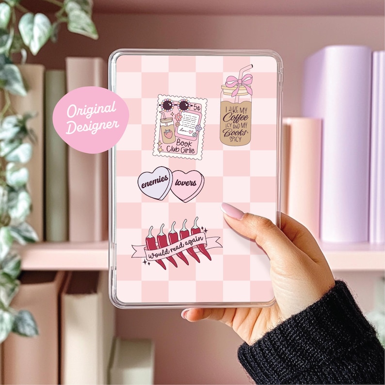 May include: A clear phone case with a pink and white checkered pattern. The case features various stickers, including a coffee drink, a stamp with sunglasses, and hearts that say "enemies" and "lovers." The text "Would read again" is also visible.