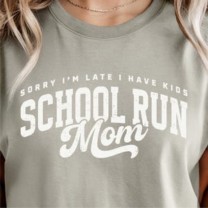 May include: Sage green crew neck sweatshirt with the text "SORRY I'M LATE I HAVE KIDS SCHOOL RUN Mom" in white. The sweatshirt is a casual style, perfect for everyday wear.