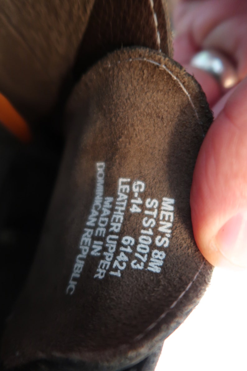 May include: Close-up of a brown leather shoe label with white text. The label reads "Men's 8M STS10073 G-14 61421 Leather Upper Made in Dominican Republic."