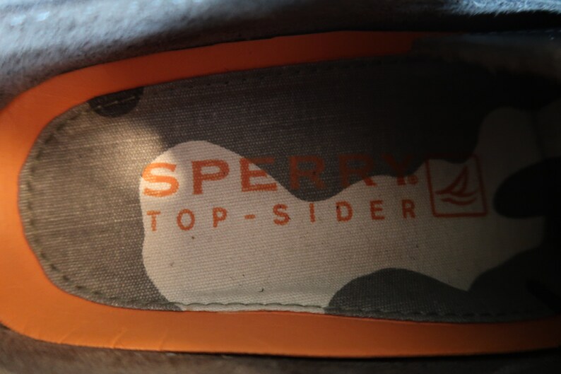 May include: Close-up of the inside of a shoe showing the Sperry Top-Sider logo with a small sailboat graphic.