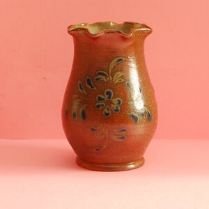 May include: A brown ceramic vase with a scalloped rim and blue and gold floral designs.