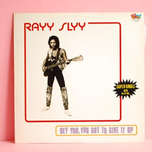 Puede incluir: Portada del álbum del sencillo de Rayy Slyy, con un músico con una guitarra. La portada tiene un borde rojo con el nombre del artista en rojo. El texto "HEY YOU, YOU GOT TO GIVE IT UP" está en la parte inferior. Una pegatina "SUPER-SINGLE" está a la derecha.
