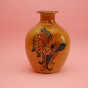 May include: A brown ceramic vase with a stylized fish design in black and brown. The vase has a rounded body and a narrow neck.