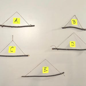 May include: Five rustic wall hangings, each featuring a natural wooden branch base and a triangular shape formed by twine. Each has a yellow sticky note with a letter from A to E.
