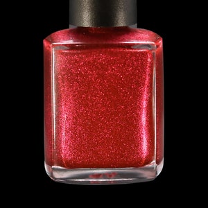 May include: A bottle of red nail polish with a black cap. The polish has a glittery, shimmering finish. The bottle is square and made of clear glass, set against a black background.