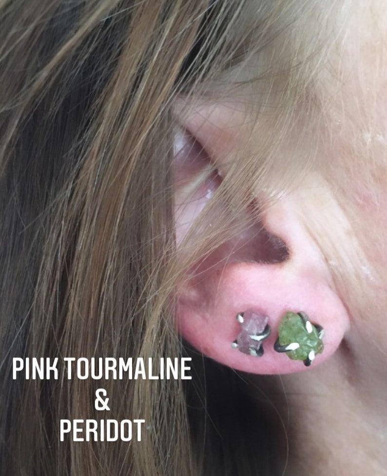 Pu&ograve; includere: Primo piano di un orecchio che indossa un paio di orecchini. L'orecchino sinistro presenta una pietra preziosa di tormalina rosa, mentre l'orecchino destro presenta una pietra preziosa di peridoto verde. Entrambi gli orecchini sono incastonati in argento.