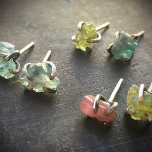 Pu&ograve; includere: Sei paia di orecchini con pietre preziose di diversi colori. Gli orecchini sono in argento e hanno un design semplice. Le pietre preziose sono verdi, rosa e gialle.