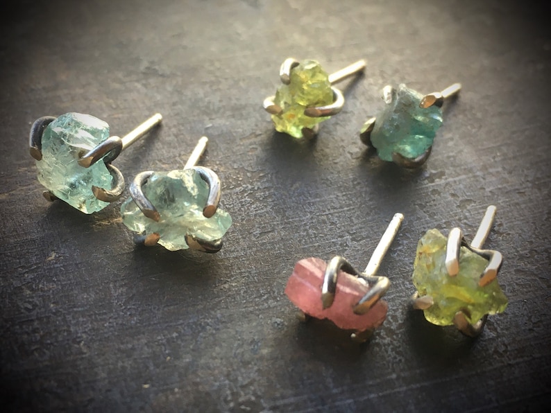 Pu&ograve; includere: Sei paia di orecchini con pietre preziose di diversi colori. Gli orecchini sono in argento e hanno un design semplice. Le pietre preziose sono verdi, rosa e gialle.