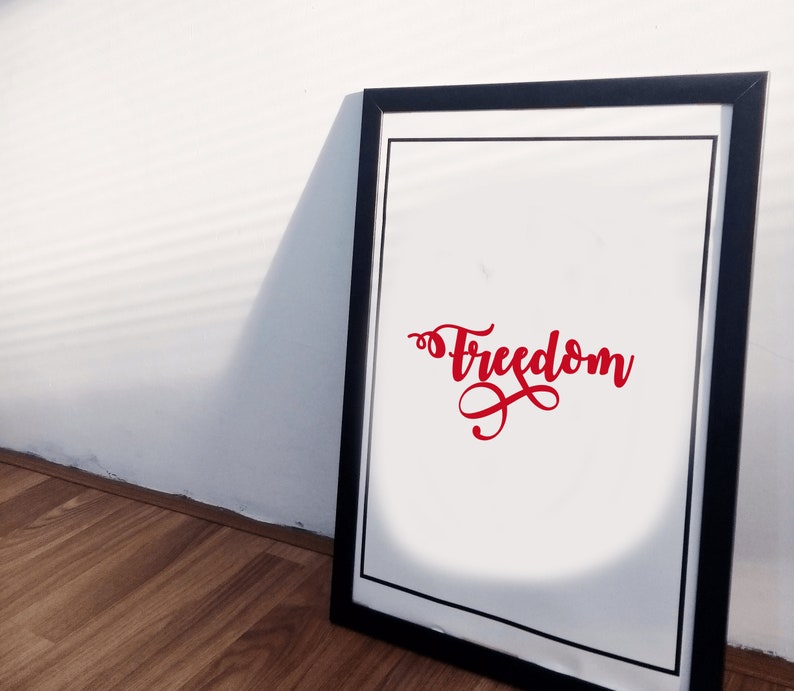 Pode incluir: Uma impress&atilde;o emoldurada com a palavra "Freedom" em escrita cursiva vermelha. A obra de arte est&aacute; sobre um fundo branco, emoldurada por uma borda preta e uma moldura preta. A impress&atilde;o est&aacute; encostada numa parede branca.