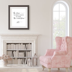 Pode incluir: Uma impressão emoldurada com fundo branco e texto preto que diz "A pedra que os construtores rejeitaram tornou-se a pedra angular" com a referência bíblica "Salmo 118:22" abaixo do texto.