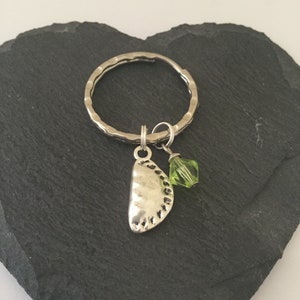 May include: A silver key ring with a charm shaped like a pastry and a green crystal bead.