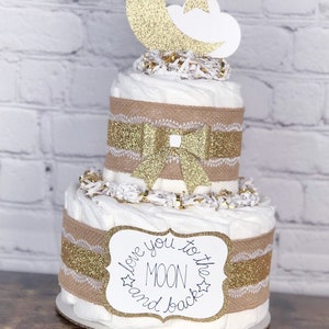 May include: Two-tiered diaper cake decorated with burlap ribbon, gold glitter, and a white sign that reads "Love you to the moon and back". The top tier is decorated with a gold glitter moon and star.