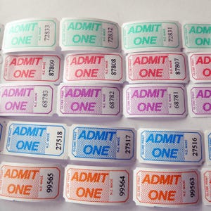 May include: A selection of "ADMIT ONE" tickets in various colours. Each ticket displays "ADMIT ONE" in a bold font, along with a unique serial number. The tickets are in shades of green, red, purple, blue, and orange.